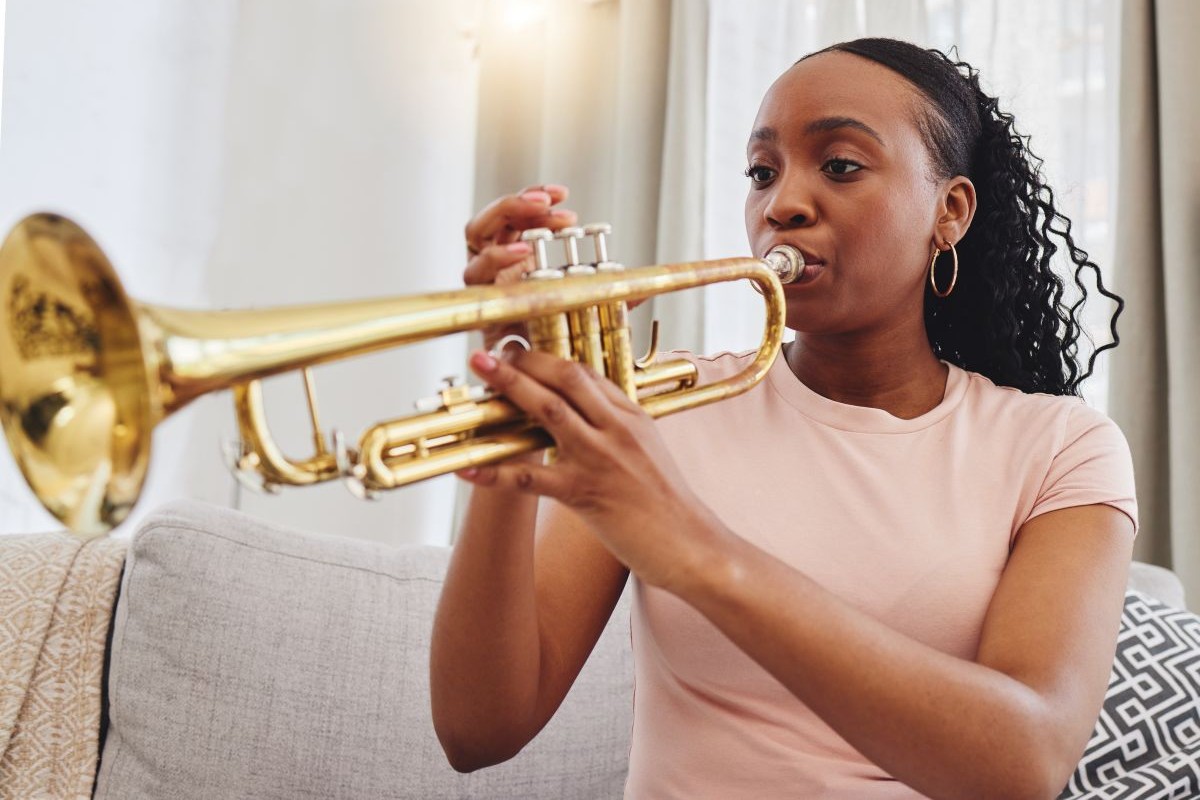A female teen playing the trumpet at home on the couch